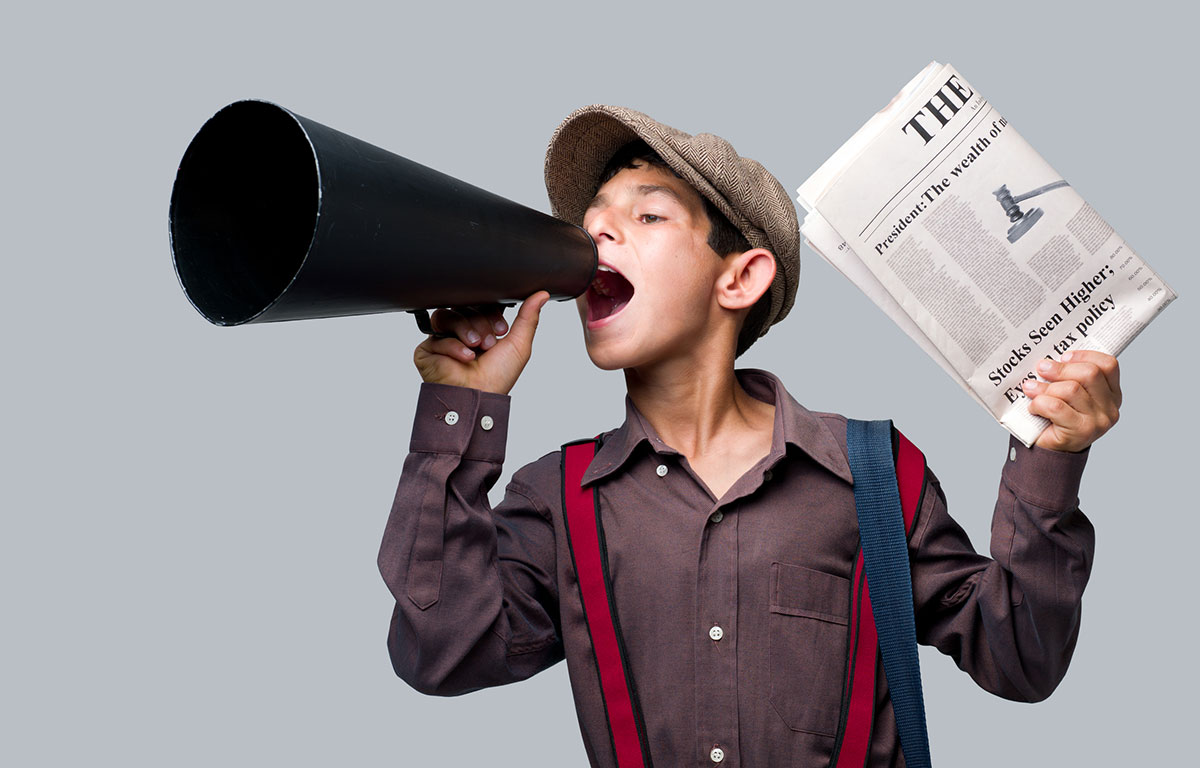 newspaper boy holding up a paper and speaking into a megaphone