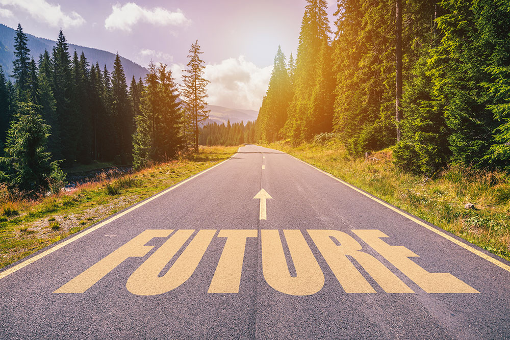 Road through woods with the word "Future" on the pavement in yellow